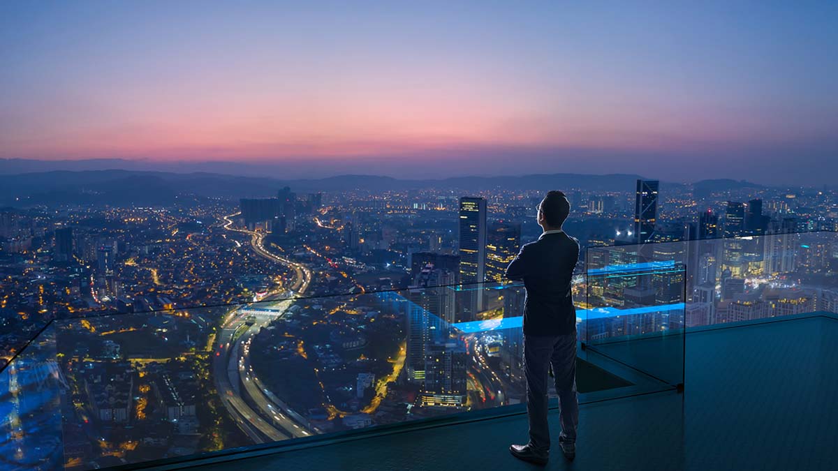 Man standing on high rise building staring at streets / freeway